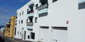 Un edificio blanco con balcones en una calle. en Estudio - descanso y bienestar en La Punta, en Punta del Hidalgo