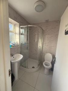 a bathroom with a shower and a toilet and a sink at The Stadium Rooms Elegant and Comfy Stay in London