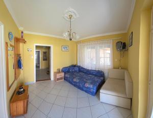 a bedroom with a blue bed and yellow walls at Panna Ház in Jászapáti