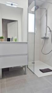 La salle de bains blanche est pourvue d'une douche et d'un miroir. dans l'établissement T3 neuf climatisé avec parking à Nice, à Nice 16 autres photos