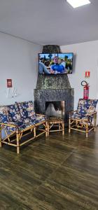 a living room with two chairs and a fireplace at POUSADA CITRINO in Ametista do Sul