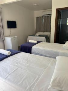 a hotel room with three beds and a television at VILA DO RIO in Santo Amaro
