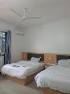 een slaapkamer met twee bedden en een plafondventilator bij Huasheng Hotel in Dar es Salaam