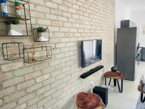 a living room with a brick wall with a tv at Place on Oak 3 in Bulawayo