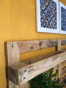 un banc en bois contre un mur jaune avec une photo dans l'établissement Inn Golegã, à Golegã