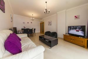 een woonkamer met een witte bank en een flatscreen-tv bij C05 - Convento Apartment in Lagos