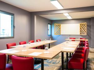 una sala de conferencias con mesas de madera y sillas rojas en ibis Styles Rouen Val De Reuil, en Val de Reuil
