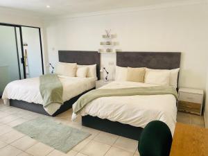 een slaapkamer met twee bedden met witte lakens bij Place on Oak 4 in Bulawayo