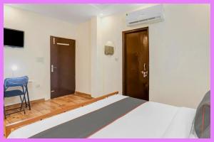 ein Schlafzimmer mit einem Bett, einem Stuhl und einer Tür in der Unterkunft Hotel Satvik Premium Near Park in Bhubaneshwar