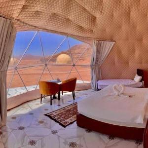 een slaapkamer met een bed, een bureau en een raam bij RUM MAREA lUXURY CAMP in Wadi Rum