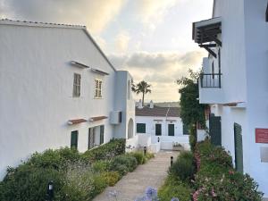 a pathway between two white buildings with flowers at Apartamentos Posidonia in Son Parc