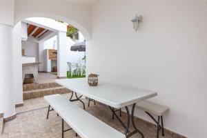 a white dining room with a white table and benches at D02 - Carrob Street House in Lagos