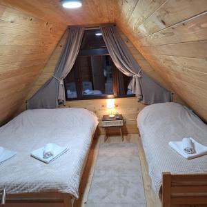 two beds in a wooden room with a window at Brvnara Gorska Dama in Sekulić 