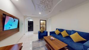 a living room with a blue couch and a tv at شقق أون يسن للشقق المخدومة in Medina