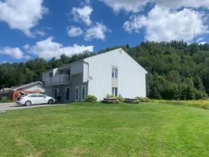 een wit huis met een auto ervoor geparkeerd bij Condos Mont-Trinité in Saint-Michel-des-Saints