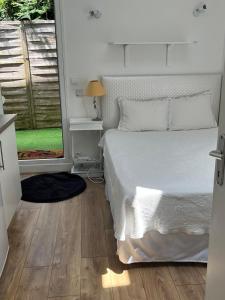 une chambre avec un lit blanc et une fenêtre dans l'établissement Chambre d'hôtes-studette Biarritz Milady, calme, patio, vue sur jardin et montagne du patio, parkin privé, tout confort, à Biarritz