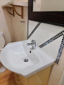 een witte wastafel in een badkamer met een spiegel bij Brando bnb in Koning Willemstad