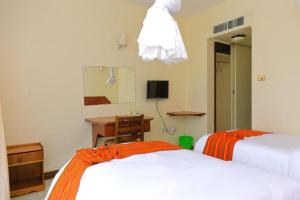 2 bedden in een kamer met een bureau en een spiegel bij Raya hotel Nyali Mombasa in Mombasa +4 foto's