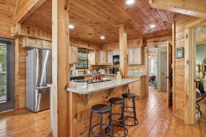 een keuken met houten kasten en een aanrecht met krukken bij The Wild Life cabin in Hatchertown +22 foto's