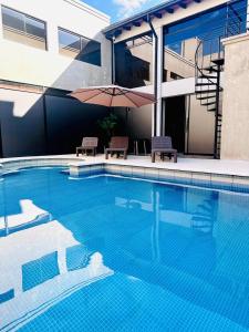 a swimming pool with two chairs and an umbrella at SBS Hotel & Spa in Asunción