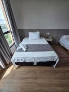 a bedroom with a bed and a large window at Flat 709 - Hotel Comfort Taguatinga in Brasília