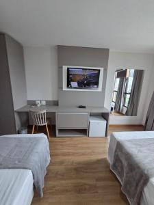 a bedroom with two beds and a tv on the wall at Flat 709 - Hotel Comfort Taguatinga in Brasília