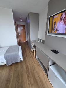 a hotel room with a bed and a flat screen tv at Flat 709 - Hotel Comfort Taguatinga in Brasília