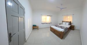 een witte slaapkamer met een bed en een deur bij JEK Villa in Brufut