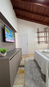 a bedroom with a bed and a tv on the wall at Pousada Vivenza in Laguna +5 photos