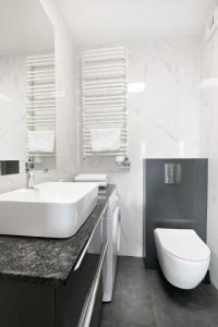 Un baño blanco con lavabo e inodoro. en Apartamenty Platinex 1, en Cracovia