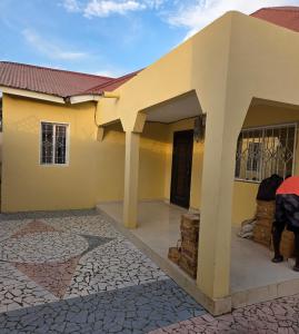 een geel huis met een veranda en een gebouw bij JEK Villa in Brufut