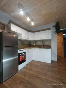 a kitchen with a stainless steel refrigerator and white cabinets at Bieszczadzkie Pola in Wańkowa +37 photos