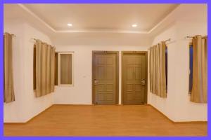 ein leeres Zimmer mit zwei Türen und Holzböden in der Unterkunft Bhoomika Premium Inn Near Railway Station in Lucknow