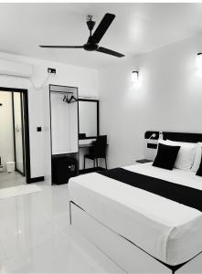 a white bedroom with a bed and a desk at Alyraa sunset in Mathiveri