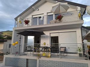 a house with a balcony with tables and umbrellas at Villa Nova Ohrid in Ohrid