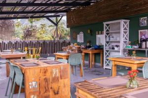 ein Restaurant mit Holztischen und -stühlen und einer grünen Wand in der Unterkunft Pousada Cahê in Ilhabela