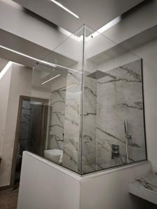 a bathroom with a glass shower with a marble wall at Lūma Retreat in Kastoria