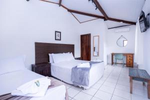 ein Schlafzimmer mit zwei Betten und einem Tisch und einem Stuhl in der Unterkunft Pousada Cahê in Ilhabela + 191 Fotos