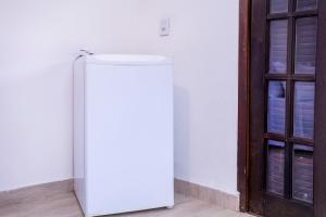 einen weißen Kühlschrank in einem Zimmer neben einer Tür in der Unterkunft Pousada Cahê in Ilhabela