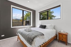 a bedroom with a bed and two windows at Luxury Hāwea, Alfresco Retreat, Sleeps 6 in Lake Hāwea