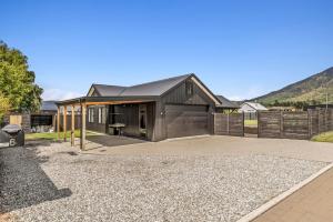 a house with a black roof on a gravel driveway at Luxury Hāwea, Alfresco Retreat, Sleeps 6 in Lake Hāwea
