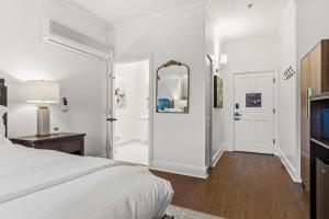 een witte slaapkamer met een bed en een spiegel bij Sonoma Stonehouse Suite 10 in Bak