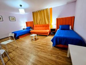 a bedroom with two beds and an orange chair at Suite Naranja moderna para 3 huéspedes Cocina equipada, Wi-Fi rápido y excelente ubicación céntrica in Mexico City