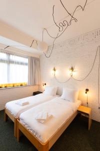a hotel room with two beds with white sheets at De Groene Afslag Kunsthotel in Bussum