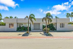 ein weißes Haus mit Palmen davor in der Unterkunft DayDream Villa in Palm-Eagle Beach
