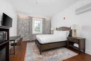 een slaapkamer met een bed, een bureau en een televisie bij Sonoma Stonehouse Hotel in Bak