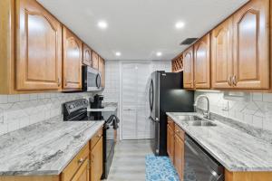 a kitchen with wooden cabinets and a black refrigerator at IMG Condo Near Golf Course in Bradenton
