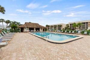 a swimming pool at a resort with chairs and a building at IMG Condo Near Golf Course in Bradenton