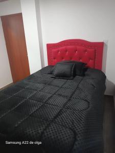 een slaapkamer met een zwart bed met een rood hoofdeinde bij Casa punta del este in Paipa