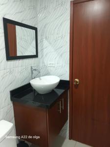 een badkamer met een wastafel en een houten deur bij Casa punta del este in Paipa